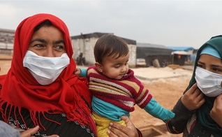 Mulheres usam máscaras em um campo para deslocados na província de Idlib. (Foto: Aaref Watad / AFP)