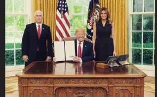Donald Trump exibe a assinatura da ordem, entre a primeira-dama Melania e o vice Mike Pence. (Foto: Reprodução/Twitter)