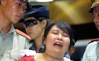 Mulher presa pela polícia comunista chinesa. (Foto: Reprodução/The Epoch Times/Getty)