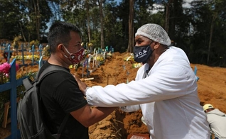 O pastor Izaías Nascimento conforta um jovem durante o funeral de seu pai. (Foto: Michael Dantas/AFP)