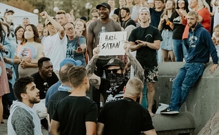 Homem segura placa com a frase “Salve Satanás” em meio a cristãos em Seattle. (Foto: Instagram/Sean Feucht)
