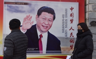 Pessoas passam por um pôster do presidente chinês Xi Jinping ao lado de uma rua em Pequim. O controle cada vez maior de Xi Jinping sobre a China já rendeu ao líder comparações com Mao Tsé Tung. (Foto: AFP / GREG BAKER)