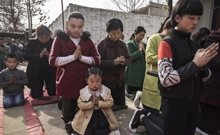 Cristãos chineses oram ajoelhados durante um culto de Páscoa em uma igreja não oficial. (Foto: Getty Images / Kevin Frayer)