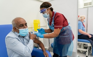 O trabalhador de uma casa de repouso, Pillary Jagambrun, de 61 anos, recebe dose da vacina da Pfizer-BioNTech contra de Covid-19 no Hospital da Universidade Croydon, no sul de Londres, na terça-feira. (Foto: PA)