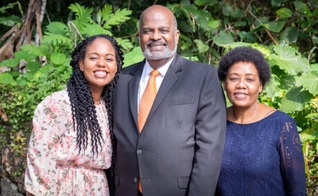 Pastor Eli Henry (ao centro), com sua esposa (à esquerda) e sua filha, Irma (à direita). (Foto: IASD News)