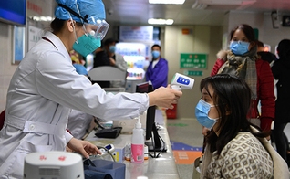 Profissional de saúde checa temperatura de mulher em um hospital de Fuzhou, na China. (Foto: Xinhua)