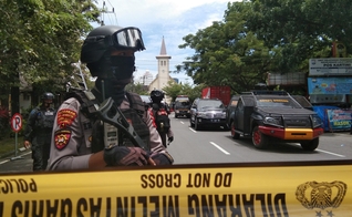 Policiais montam guarda ao longo de uma rua fechada após explosão em frente a igreja, na Indonésia. (Foto: Antara Foto/Arnas Padda via Reuters)