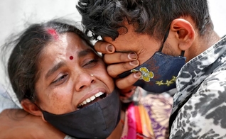 Mulher chora com seu filho depois que seu marido morreu devido à Covid-19 fora de um necrotério em Ahmedabad, na Índia. (Foto: Amit Dave / Reuters)