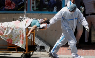 Profissional de saúde leva paciente com Covid-19 em hospital de Nova Delhi, na Índia, neste sábado (24). (Foto: Adnan Abidi/Reuters).