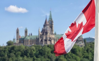 Bandeira canadense, com o parlamento ao fundo. (Foto: Reprodução / Shutterstock)