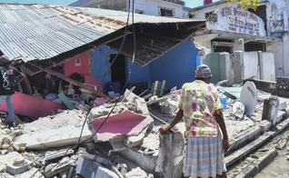 Mulher observa o que sobrou de uma casa que desabou no terremoto deste sábado (14), em Les Cayes, no Haiti. (Foto: Duples Plymouth/AP)