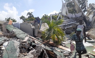 Pessoas caminham entre escombros de casas destruídas pelo terremoto em Les Cayes, no Haiti. (Foto: Jose Flecher/Reuters).