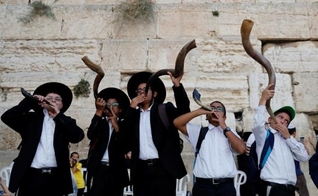 Judeus ultraortodoxos tocam o shofar enquanto os fiéis oram no Muro das Lamentações. (Foto: Reprodução / El País)