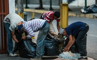 Pessoas vasculham lixo em busca de comida nas ruas de Caracas. (Foto: Getty Images)