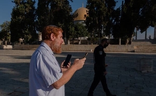 O rabino Yehudah Glick orando no Monte do Templo, em agosto de 2021, enquanto um policial patrulhava nas proximidades. (Foto: Amit Elkayam/The New York Times).