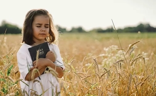 Menina segura sua Bíblia. (Foto: Getty Images / Anastasiia Stiahailo)