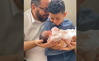 Momento em que João Prudêncio Neto e seu filho Davi recebem a pequena Giovanna nos braços. (Foto: Captura de tela/Vídeo Facebook)