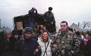 Paula O'Keefe entre soldados que protegem a distribuição de alimentos em um campo de refugiados chechenos. (Foto: Reprodução / Premier)