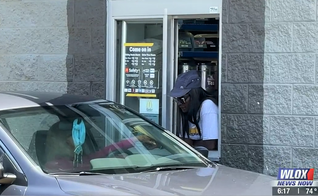 Brenda Wilson oferece orações a quem passa pelo drive thru, em Ocean Springs. (Foto: Reprodução/WLOX-TV).