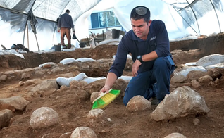 Kfir Arbiv, diretor de escavação da Autoridade de Antiguidades de Israel, limpa uma pedra balista no Complexo Russo. (Foto: Yoli Schwartz/Israel Antiquities Authority)