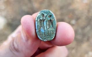 O escaravelho, mostrando uma figura sentada à direita e uma figura em pé com o braço erguido à esquerda. (Foto: Gilad Stern/Israel Antiquities Authority)