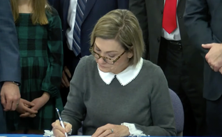 A governadora de Iowa, Kim Reynolds, enquanto assina nova legislação. (Captura de tela/ YouTube/We Are Iowa Local 5 News)