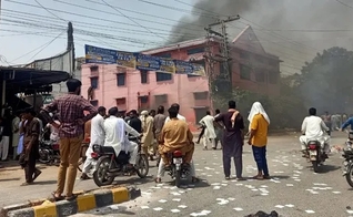 Uma multidão observa a fumaça subir de uma igreja incendiada em Jaranwala, Paquistão, em 16 de agosto de 2023. (Foto: Daud Irshad)
