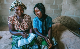 Safiratu e a filha estudando a Bíblia. (Foto: Reprodução/Global Christian Relief)