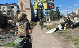 Soldado ucraniano escolta missionários por uma cidade destruída nos arredores de Pokrovsk. (Foto: Free Burma Rangers)