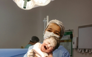 Profissional de saúde segura recém-nascido instantes após o parto. (Foto: Jonathan Borba/Unsplash)