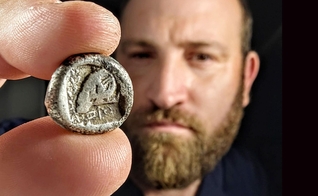 Yanniv David Levy, especialista em moedas da Autoridade de Antiguidades de Israel, segura a rara moeda de cerca de 2.500 anos. (Foto: Shai Halevi/Autoridade de Antiguidades de Israel)