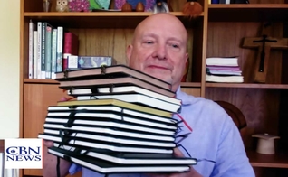 Don Ashley mostra os cadernos preenchidos à mão durante seu projeto de copiar todo o Novo Testamento. (Foto: CBN News)