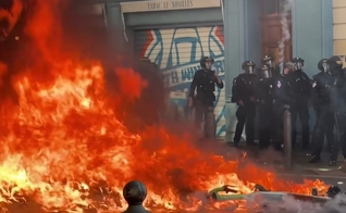 Incêndio durante protestos violentos na França, diante de policiais mobilizados para conter os distúrbios. (Captura de tela/CBS Pittsburgh)