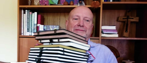 Don Ashley mostra os cadernos preenchidos à mão durante seu projeto de copiar todo o Novo Testamento. (Foto: CBN News)
