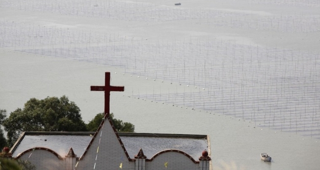 Uma igreja é vista ao lado de uma fazenda de lavatório na vila de Gutong, no município de Sansha, no condado de Xiapu, na província de Fujian, China. (Foto: Getty Images/China Photos)