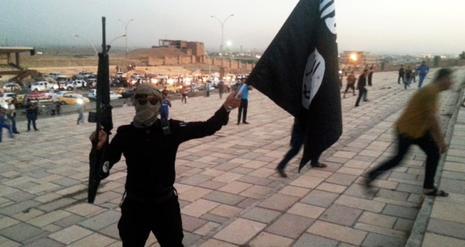 Militante do Estado Islâmico levanta bandeira do grupo terrorista no Iraque, país onde as casas de cristãos foram marcadas com o mesmo sinal correspondente à letra 'N' do alfabeto ocidental, como sigla para a palavra "nazareno" (Foto: Reuters)