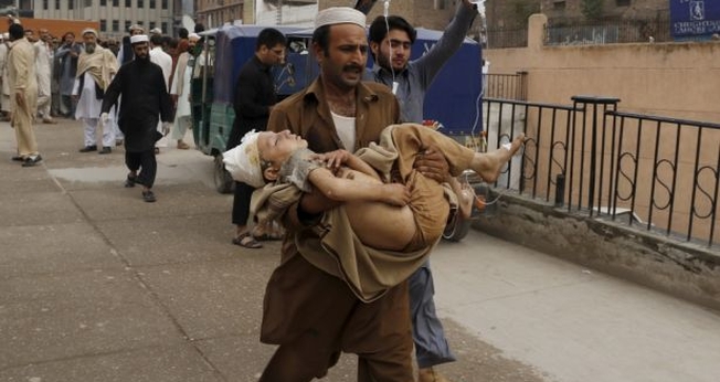 Homem carrega garoto ferido, após o terremoto, em Peshawar, no Paquistão (Foto: Reuters)
