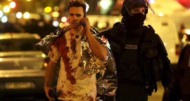 Policial acompanha vítima do ataque à casa de shows 'Bataclan', em Paris. (Foto: Reuters)