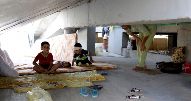 Crianças cristãs que fugiram da violência do Estado Islâmico em Qaraqosh, descansam sobre colchões velhos, em prédio abandonado, na região de Arbil - norte de Bagdá. (Foto: Reuters)