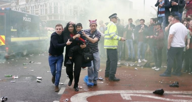 Imagem registrou momento em que Paul Sanderson (à direita) e outro homem ajudaram mãe e filho a fugir do tumulto gerado por torcedores antes de um jogo de futebol na Inglaterra. (Foto: Reuters)