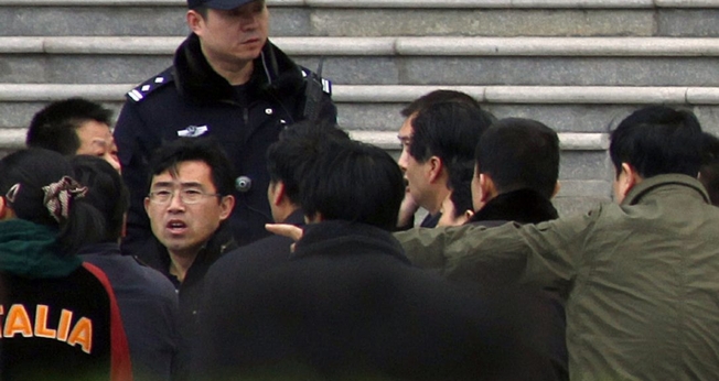Policiais à paisana cercam um homem que estava dentro de uma igreja, em Pequim. (Foto: David Gray/Reuters)