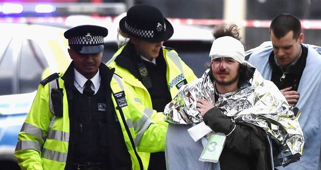 Policiais britânicos socorrem homem ferido em ataque, em Londres. (Foto: El País)