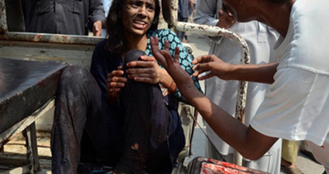 Kashmala Munawar segura sua perna, após ser socorrida próximo à igreja bombardeada no Paquistão. (Foto: British Pakistani Christian Association)