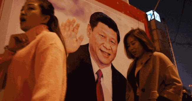 Pessoas passam por foto do presidente Xi-Jinping, exposta em rua da China. (Foto: Breitbart)