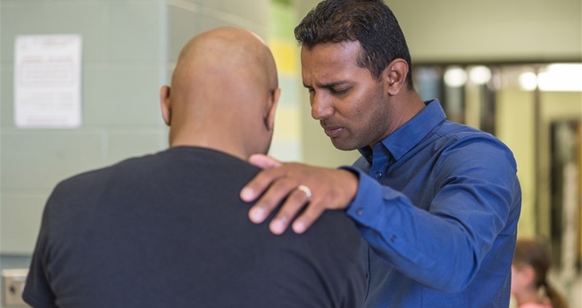 Kesavan Balasingham orando por um homem em sua igreja em Toronto, no Canadá. (Foto: NAMB)