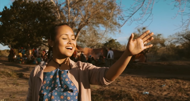 Bruna Karla se apresenta cantando e dançando juntamente com locais de Moçambique. (Foto: Reprodução).