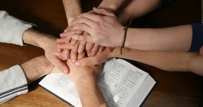 Mãos unidas sobre a Bíblia simbolizando a unidade da Igreja. (Foto: myocn.net)