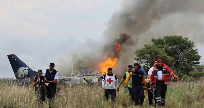 Socorristas carregam ferido em maca durante resgate após acidente com avião da Aeroméxico. (Foto: Red Cross Durango/AP)