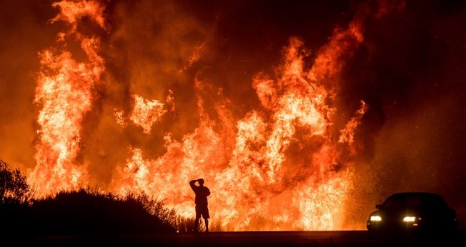 Motorista assiste as chamas do incêndio Thomas ao norte de Ventura, na Califórnia. (Foto: AP/Noah Berger)
