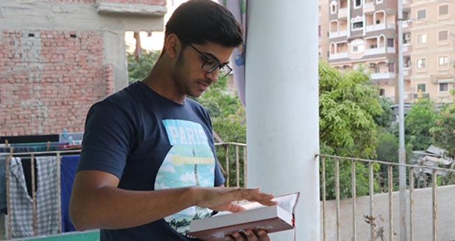 Marcos lê a Bíblia de seu pai, que ainda guarda como lembrança, após o assassinato, no Egito. (Foto: Portas Abertas/EUA)